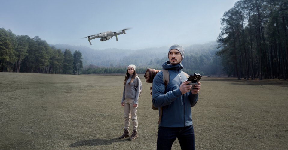DJI Air 2 S mężczyzna kontrolujący drona i kobieta stojąca na środku polany