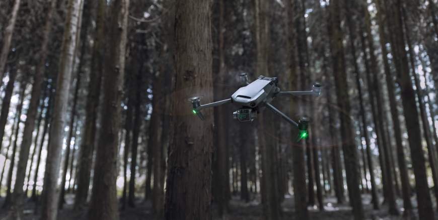lecący dron DJI Mavic 3 na tle lasu